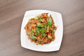 wok stir fried kway teow rice noodle mee goreng with vegetable in spicy soy chilli sauce on wood background asian halal vegan menu