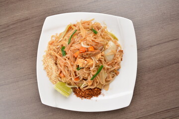wok stir fried kway teow rice noodle mee goreng with vegetable in spicy soy chilli sauce on wood background asian halal vegan menu