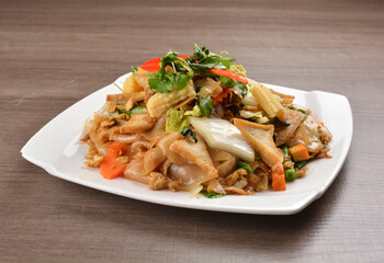 wok stir fried kway teow rice noodle mee goreng with vegetable in spicy soy chilli sauce on wood background asian halal vegan menu