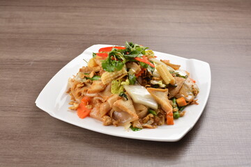 wok stir fried kway teow rice noodle mee goreng with vegetable in spicy soy chilli sauce on wood background asian halal vegan menu