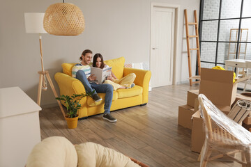Young couple reading magazine in their new house on moving day