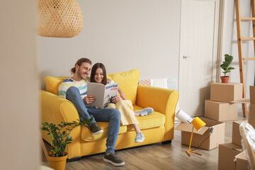 Young couple reading magazine in their new house on moving day