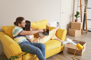 Young couple using laptop in their new house on moving day