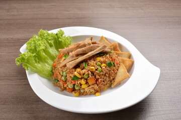 vegetarian nasi goreng fried rice with pineapple, vegetables meat in spicy chilli sambal sauce on wood background asian halal vegan menu