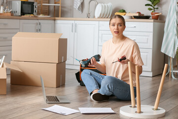 Troubled young woman assembling furniture at home