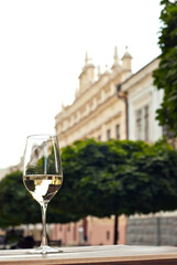 Glass of white wine close up. Alcoholic drink on a wooden table on a background of the city. Transparent wine on the summer terrace of the restaurant.