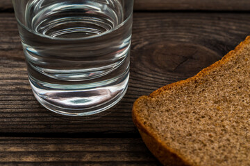 Shot of vodka with a piece of black bread on an old wooden table. Close up view