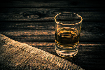 Glass of tequila with piece of cloth on an old wooden table. Close up view