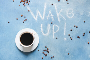 Cup of coffee with beans and text WAKE UP on color background