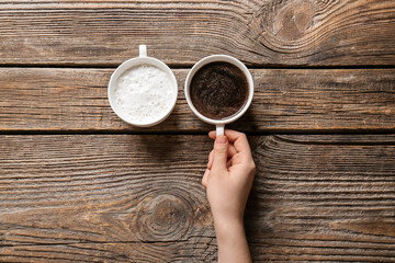 Woman with cups of coffee on wooden background