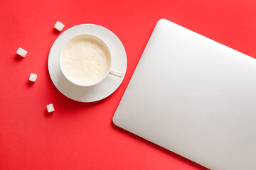Obraz na płótnie Canvas Cup of coffee with sugar and laptop on color background