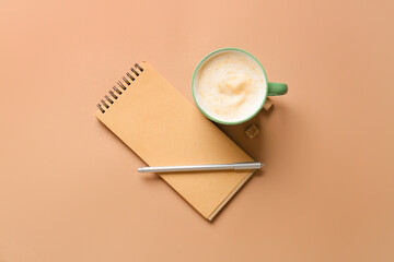 Cup of coffee with pen and notebook on color background
