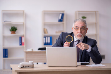 Old male employee sitting at workplace