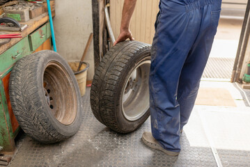 Fototapeta premium Mechanic changing tire in car service. Tire rotation machine.Car mechanic mounts tire on wheel in a workshop.