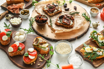 Composition with different tasty bruschettas and ingredients on light background, closeup