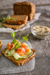 Tasty bruschetta with cucumber and salmon on grunge background