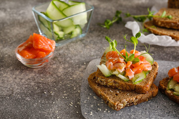 Tasty bruschetta with cucumber and salmon on grunge background