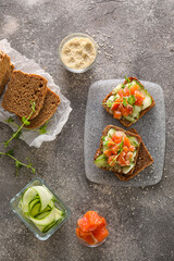 Tasty bruschettas with cucumber and salmon on grunge background