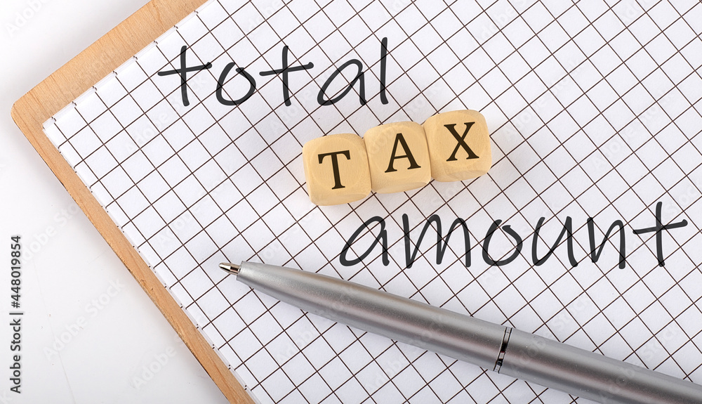 Poster total tax amount text concept written on the wooden cubes blocks and notebook