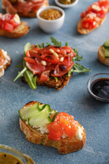 Different tasty bruschettas and ingredients on color background