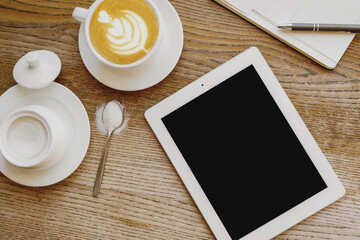 Top view of cup of coffee with organizer and digital tablet on table.