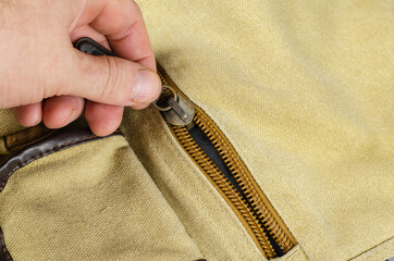 Close-up of a man's hand closing the zipper on the pocket of a s © Mikhail