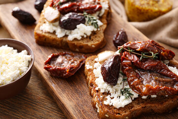Tasty bruschettas with cheese, sun-dried tomatoes and dates on table, closeup