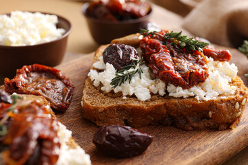 Tasty bruschettas with cheese, sun-dried tomatoes and dates on table, closeup
