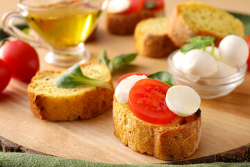 Tasty bruschettas with mozzarella cheese and tomatoes on wooden board, closeup