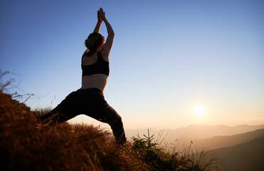 Woman doing exercise for stretching on fresh air at sunset. Concept of yoga time on nature.