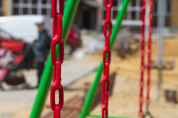 Fototapeta na wymiar Chains covered with red rubber coating for safety on swings in the playground