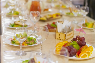 A feast in a cafe, a Russian holiday, the table is covered with glasses, Fruit, plates with salad