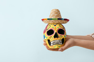 Hands with painted human skull for Mexico's Day of the Dead (El Dia de Muertos) and sombrero on...