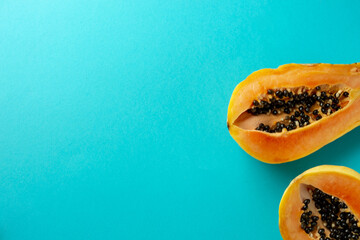 Summer composition. Tropical papaya fruits cut in half lie on a blue background. Summer concept. Flat lay, top view, copy space
