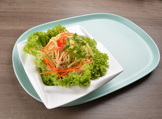 thai cold mango papaya vegetable salad in spicy sour lime sauce on wood background asian halal vegan menu
