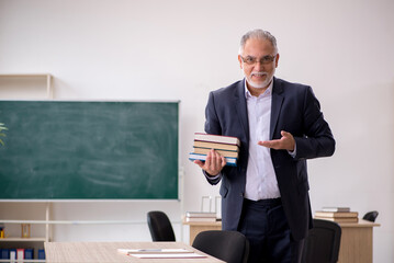 Old male teacher in front of blackboard