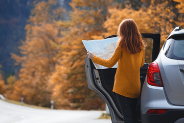 girl with a map is standing near the car