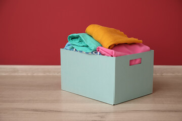 Wardrobe box with clothes near color wall