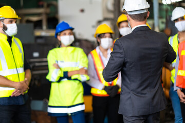 Group of engineers Workers wear protective face masks for safety in machine industrial factory. Worker man wearing face mask prevent covid-19 virus and protective hard hat.