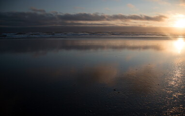 Clouds reflections in water on sunset near Westport Jetty