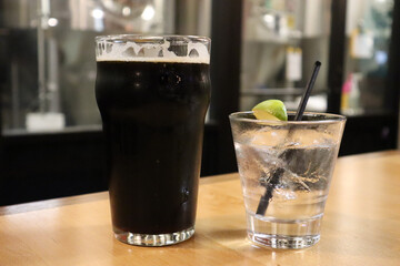 Closeup shot of dark beer and a gin cocktail with lime garnish at a brewery in Utah, USA