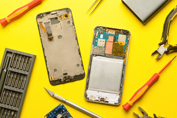 Disassembled mobile phone with technician tools on color background