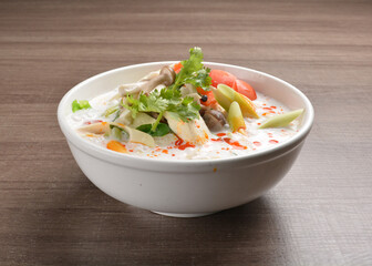cook hot and spicy white coconut curry laksa soup with mushroom and mixed vegetables in white bowl on wood background asian halal vegan menu