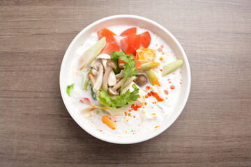 cook hot and spicy white coconut curry laksa soup with mushroom and mixed vegetables in white bowl on wood background asian halal vegan menu