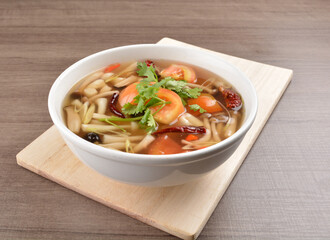 cook hot and spicy tom yum soup with mushroom and mixed vegetables in white bowl on wood background asian halal vegan menu