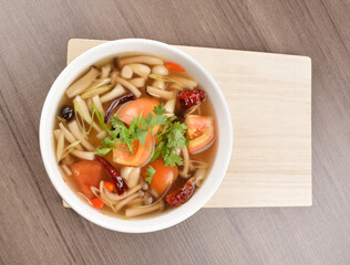 cook hot and spicy tom yum soup with mushroom and mixed vegetables in white bowl on wood background asian halal vegan menu