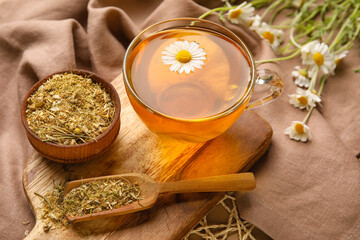 Composition with cup of chamomile tea and dried flowers on table