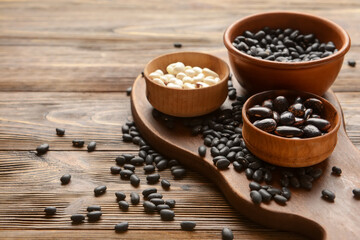 Naklejka premium Bowls with different types of beans on wooden background