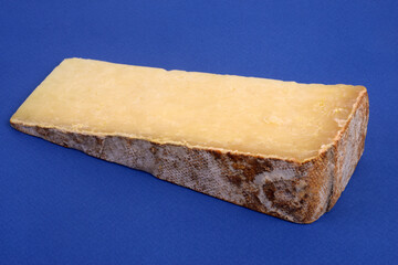 Morceau de fromage de Laguiole en gros plan sur fond bleu