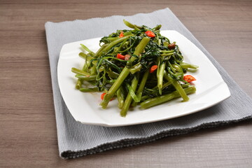 stir fried spicy sambal chilli sauce kang kong vegetables on wood background asian halal vegan menu